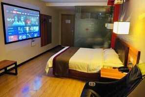 A hotel room with a bed, a TV displaying a movie, a bedside table, and a chair. - Shankee Chain Hotel (Zhuhai Jing'an Bridge) (Zhuhai)