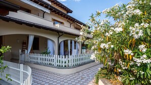Un bâtiment à deux étages doté d’un balcon, d’une clôture blanche en bois et d’une terrasse carrelée.