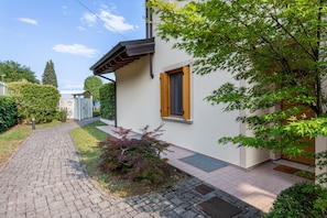 A residential building with a paved pathway, a small garden, and a wooden door.