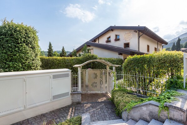 Une maison dotée d’une entrée sécurisée par un portail, d’une allée pavée et d’un jardin bien entretenu.