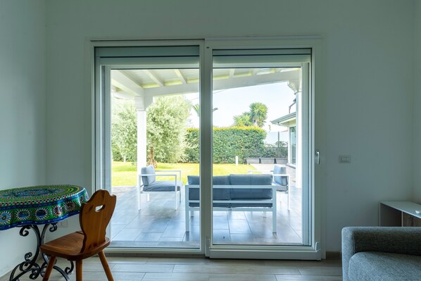 Una habitación con puerta de vidrio corredera que da a un patio exterior con mesa, sillas y sofá.