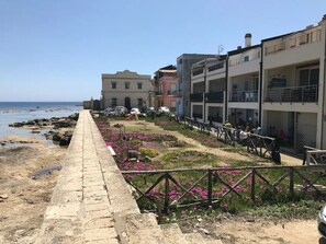 Une promenade en bord de mer bordée de bâtiments, avec un sentier en pierre et une clôture.
