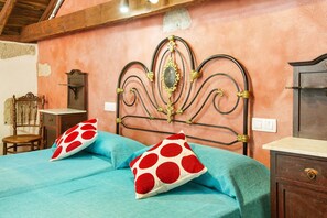 Ein Schlafzimmer mit einem Bett, zwei Kissen, einem Holzstuhl, einem Nachttisch und einer Kommode.