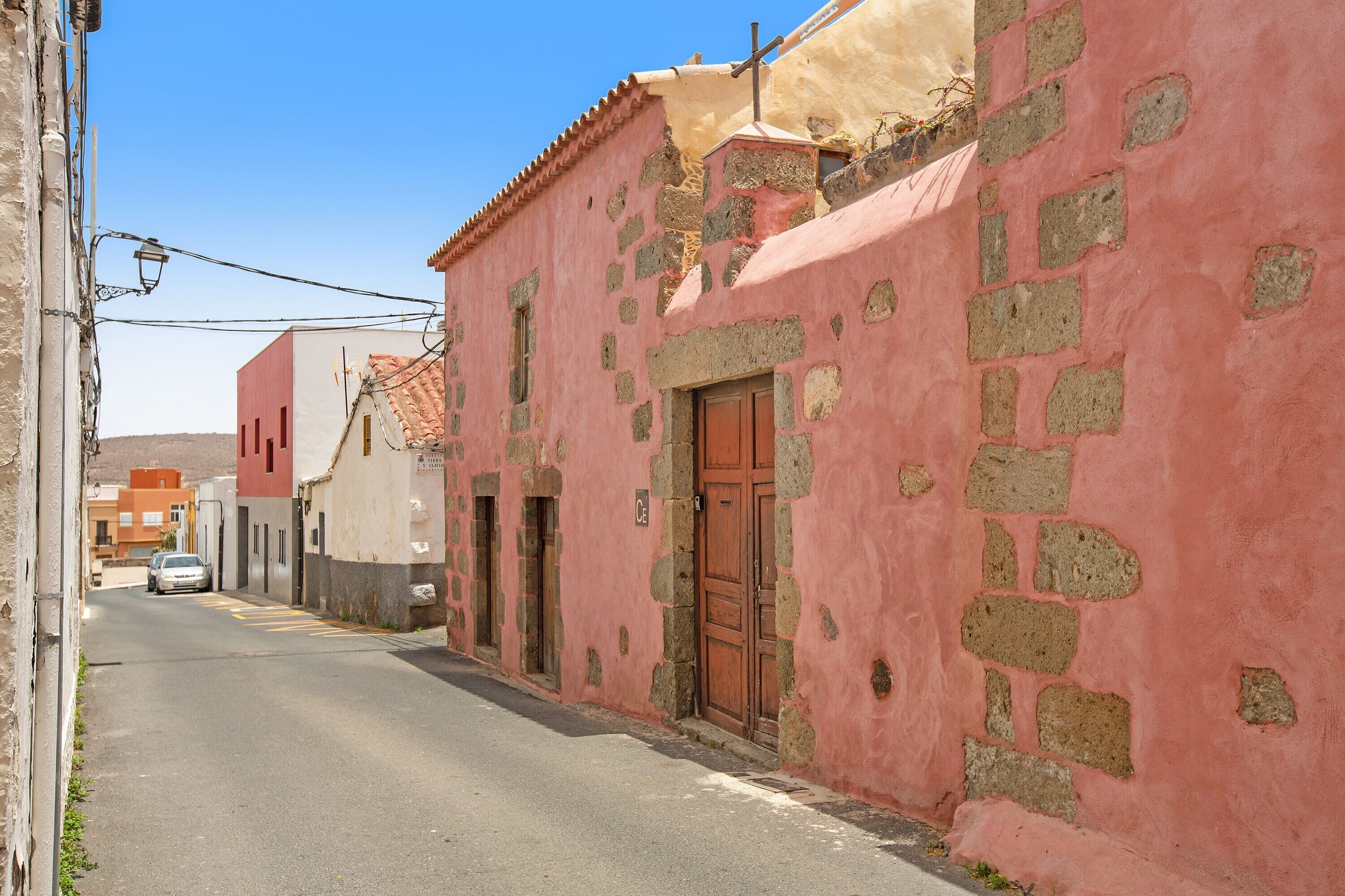 Eine enge Straße mit in Rosa und Beige gestrichenen Gebäuden, mit Steinmauern und traditionellen Türen.