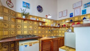 A kitchen with patterned tiles, wooden cabinets, a sink, and various kitchen items on shelves.