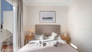 Una camera d'albergo con un letto, due comodini, un quadro appeso e vista dalla finestra.