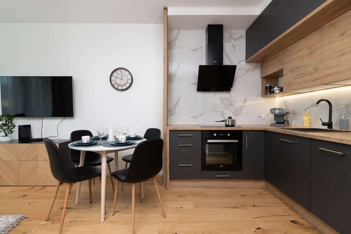 A modern kitchen with dark cabinets, a wooden countertop, a built-in oven, and a black range hood.