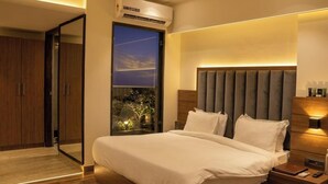 Ein modernes Schlafzimmer mit einem großen Bett, einem Nachttisch, einer Klimaanlage und Blick ins Freie.