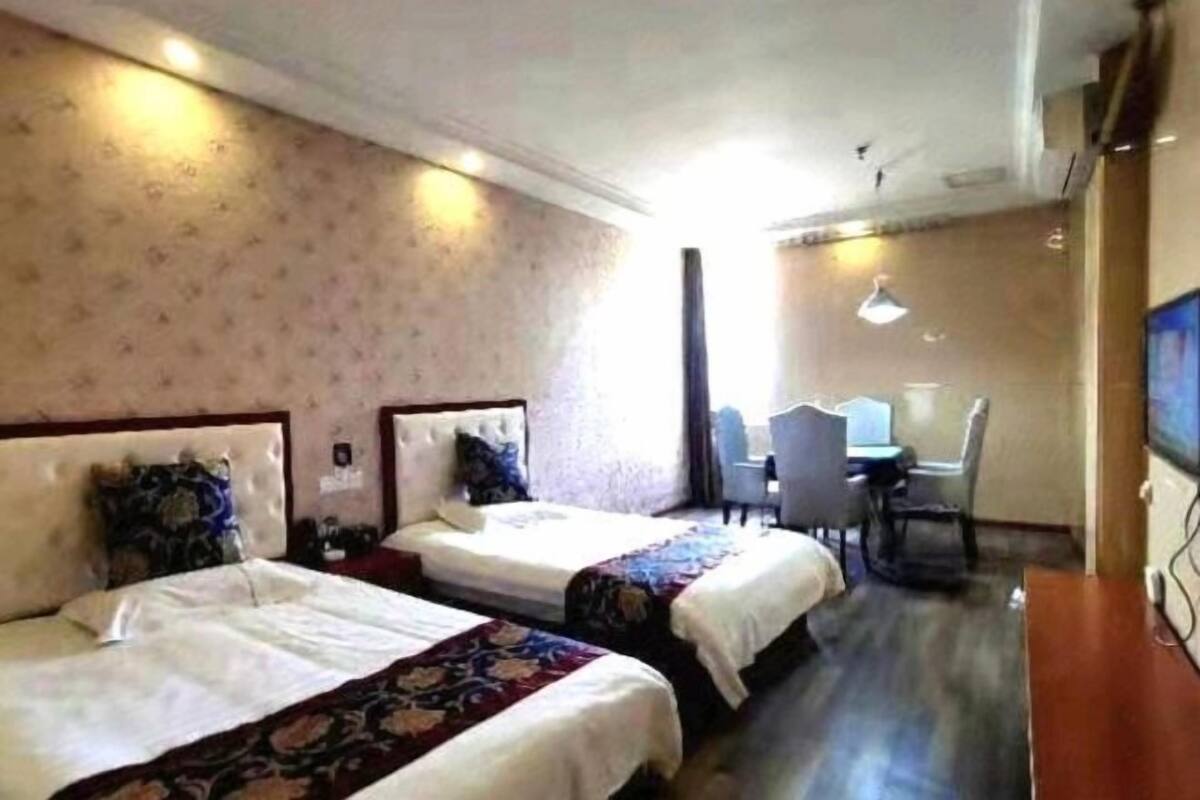 A hotel room with two beds, a desk, and a chair.