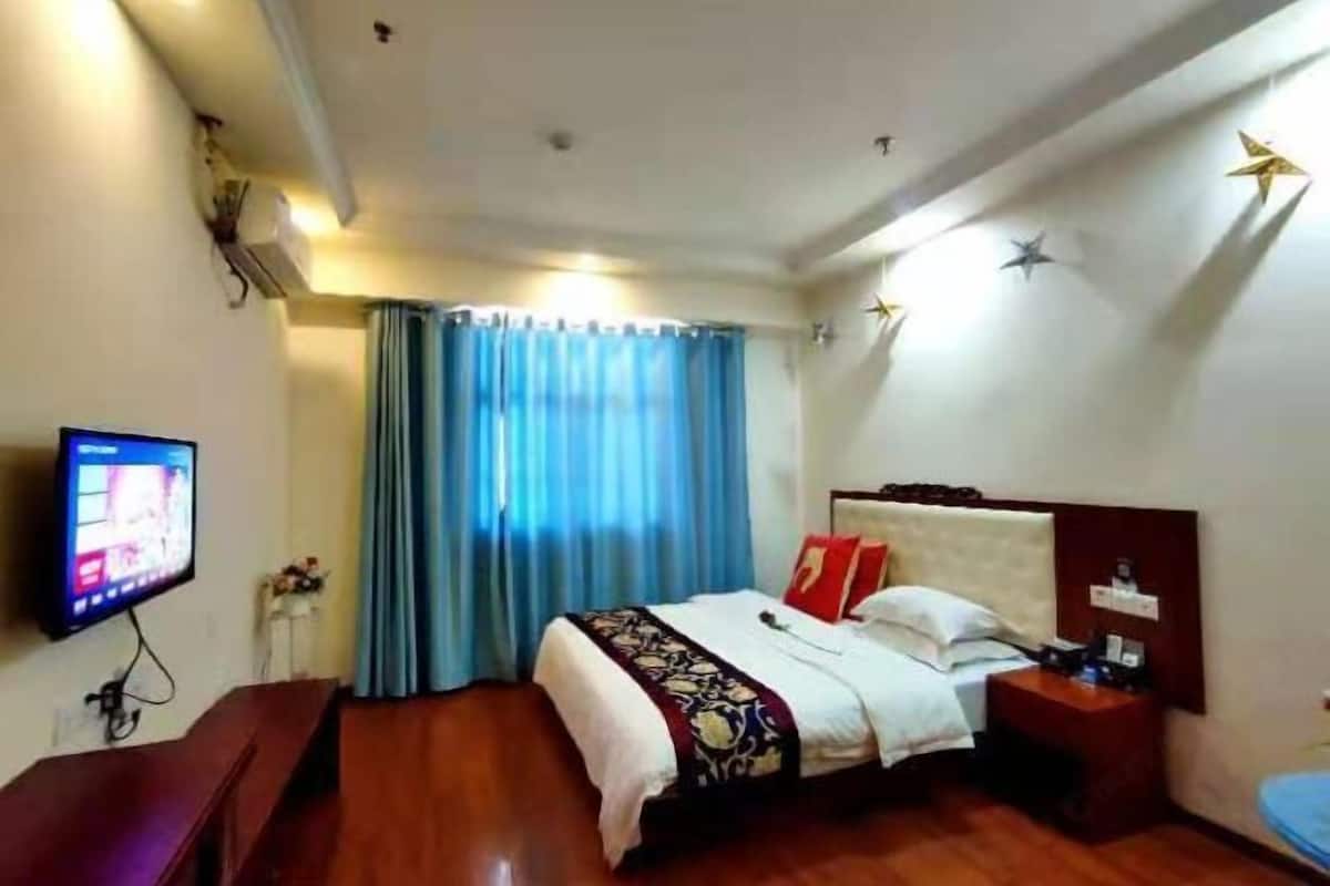 A hotel room with a bed, a TV, a desk, and a nightstand.