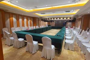 A conference room with a long table and rows of white-covered chairs, equipped with a projector and a screen. - Vienna International Hotel (Jilin Guotou Zhongdong) (Jilin City)