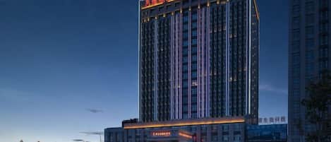 Un grand hôtel, un immeuble de grande hauteur, doté d’une enseigne lumineuse et d’une entrée imposante.