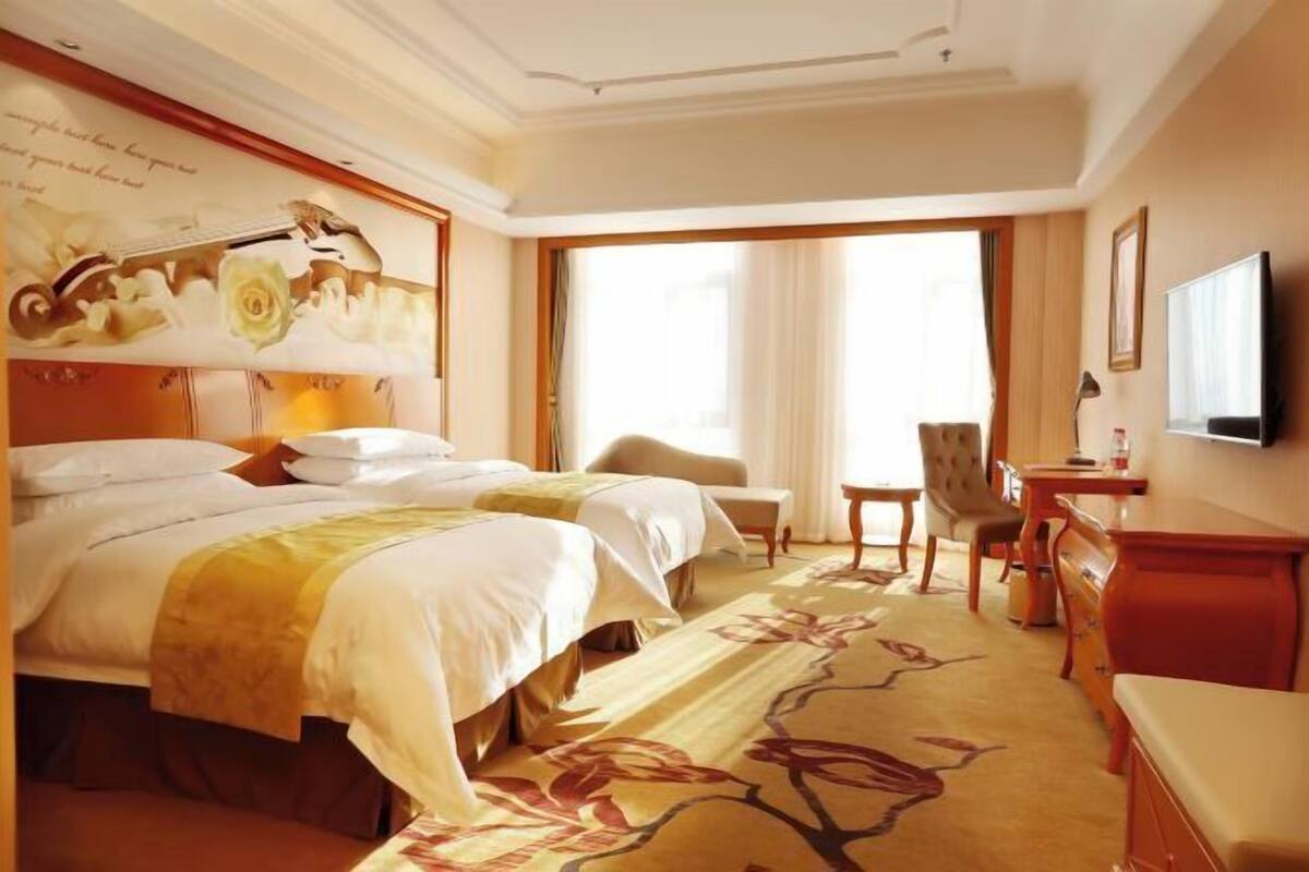 Una habitación de hotel con una cama grande, un escritorio, una silla y un televisor.