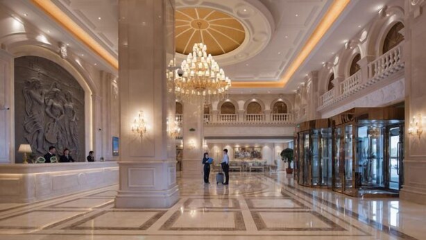 A spacious lobby with a grand chandelier, marble flooring, and a reception area with a large statue. - Vienna International Hotel (Jilin Guotou Zhongdong) (Jilin City)