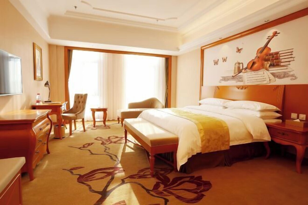 Habitación de hotel con una cama grande, un escritorio, una silla y un televisor.