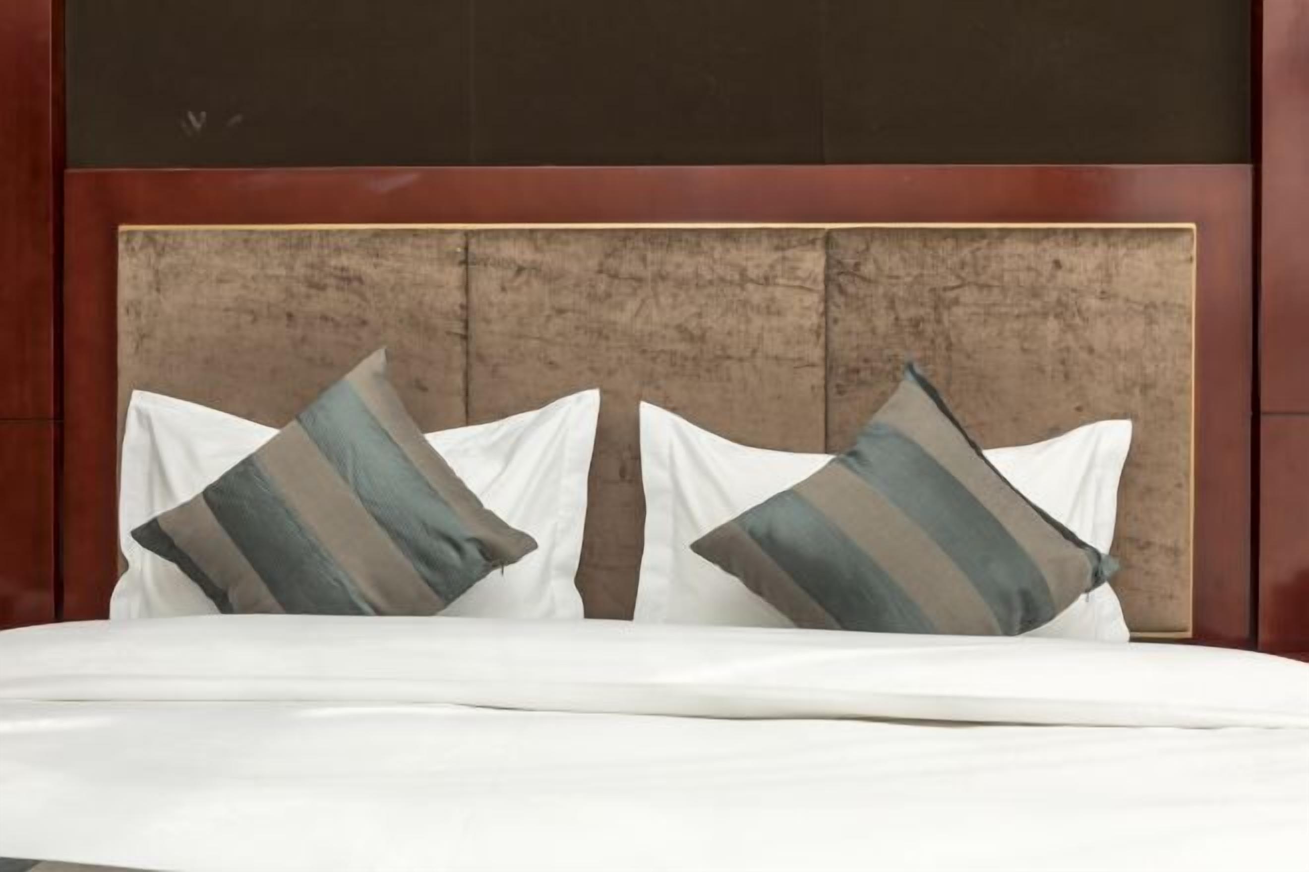 A bed with white bedding and two pillows with striped patterns.