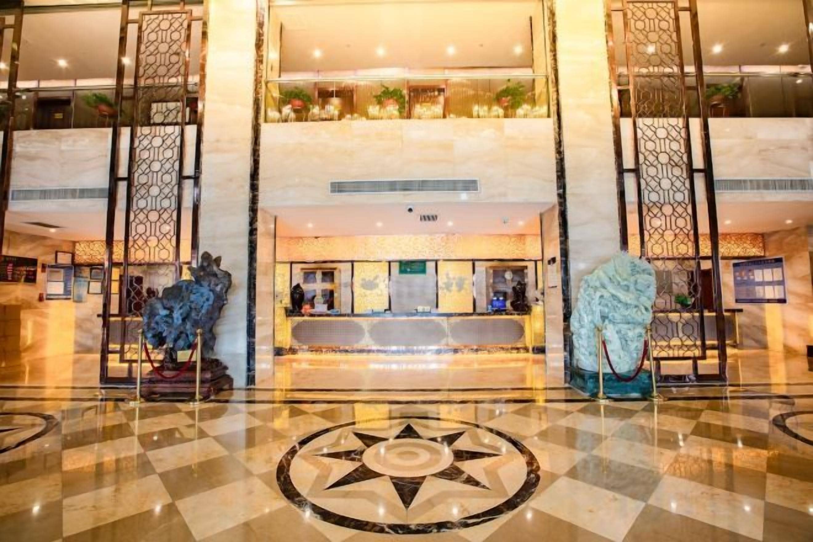 Vestíbulo de hotel con mostrador de recepción, una fuente decorativa y piso con diseño.