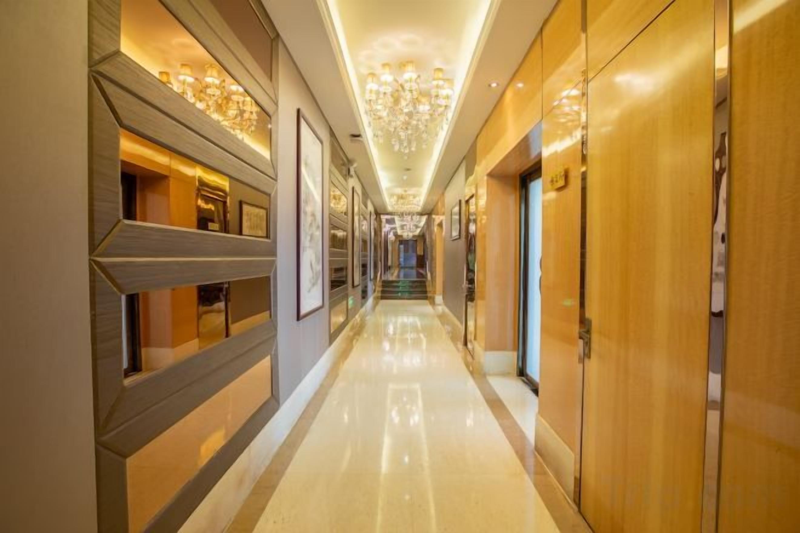 A long, well-lit hallway with wooden doors and framed pictures on the walls.