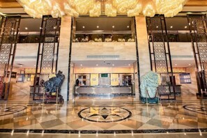 A hotel lobby with a reception desk, a large chandelier, and a check-in counter.