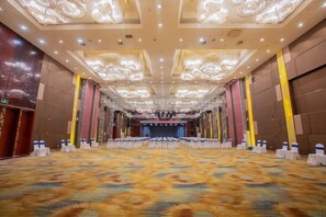 A large conference room with a patterned carpet, a stage, and rows of tables with chairs. - Baiyun Hotel (West Building) (Lanzhou)
