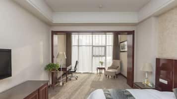 Habitación de hotel con cama, televisión, escritorio, silla, mesita y ventana.