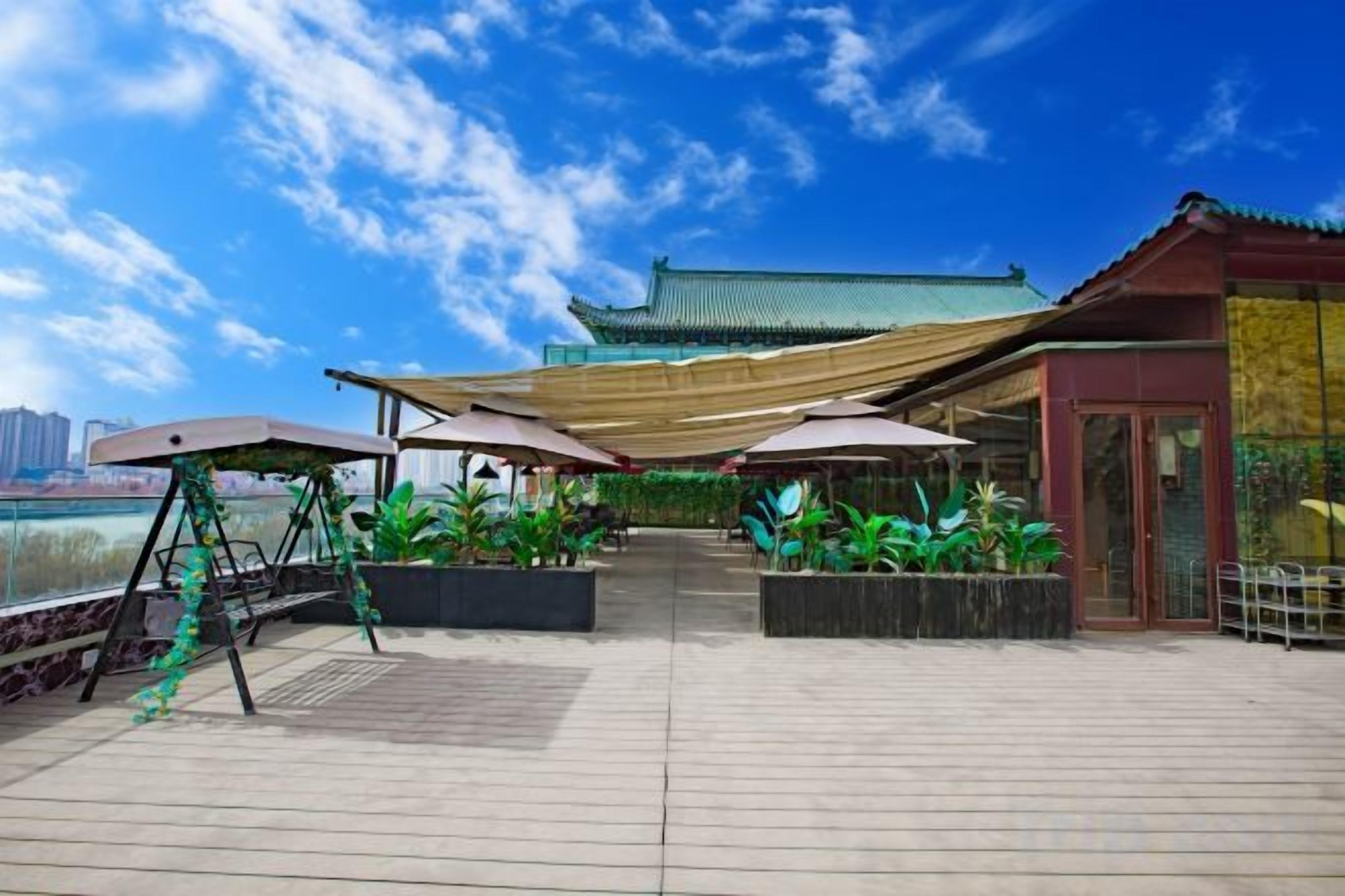 Una terraza en la azotea con mobiliario exterior, un edificio tradicional al fondo y vistas del horizonte de la ciudad.