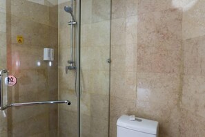 Ein Badezimmer mit Duschkabine aus Glas, Toilette und Handtrockner.