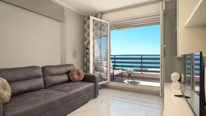 A modern living room with a grey sofa, a glass door leading to a balcony with a view of the sea. - Sun Spalato Blic (Split)