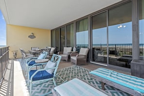 A balcony with wicker furniture, a welcome sign, and a view of the ocean.