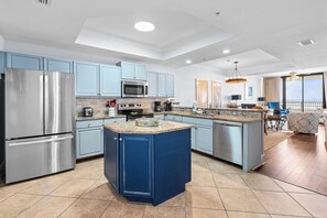 Une cuisine moderne dotée d’un îlot central, d’appareils électroménagers en acier inoxydable et de meubles de couleur bleu clair.