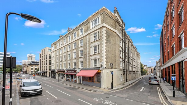 A corner building with multiple stories, a red awning, and a clear blue sky.