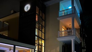 A multi-story building with a pool, a balcony with white balustrades, and a clock on the facade. - Elena Boutique Residence (Larnaca)