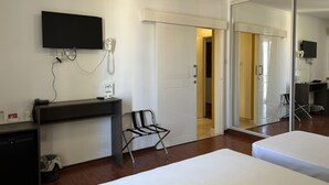 A hotel room with a bed, a desk with a phone, a chair, a TV, and a mirror. - Elena Boutique Residence (Larnaca)