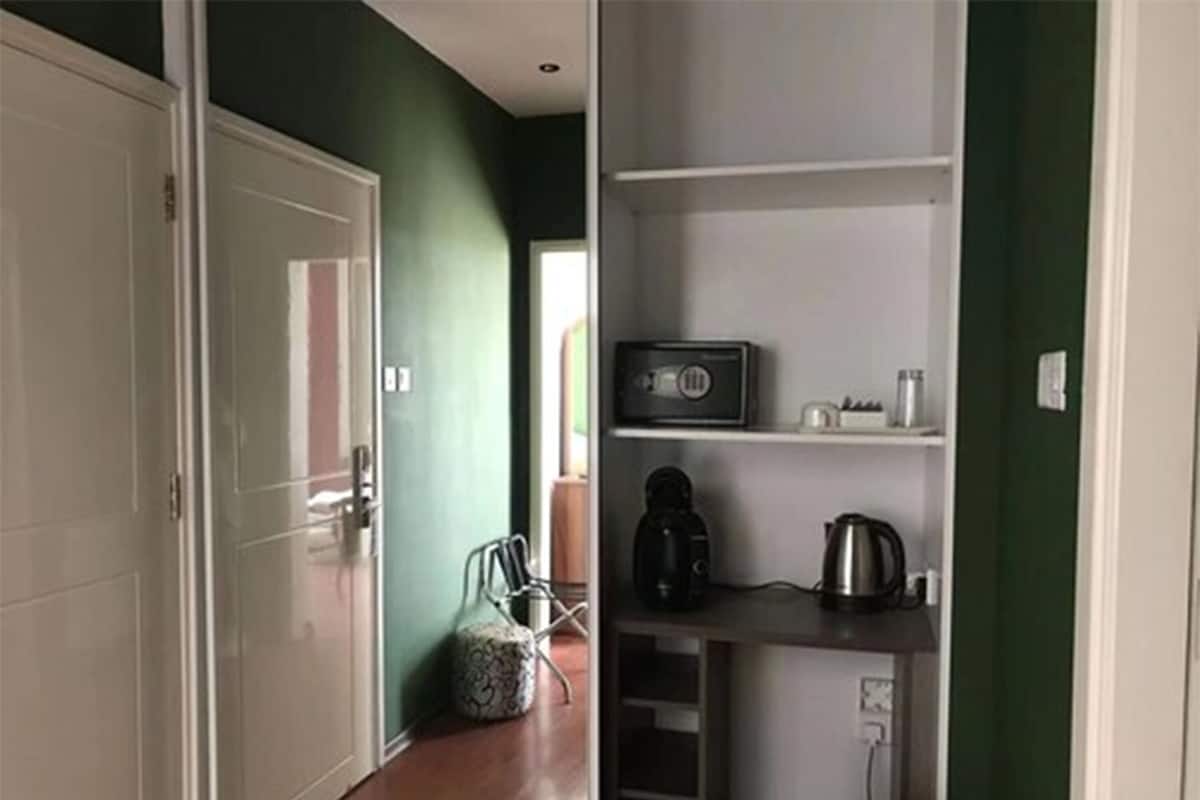 Una cocina compacta con microondas, cafetera y hervidor sobre una estantería.