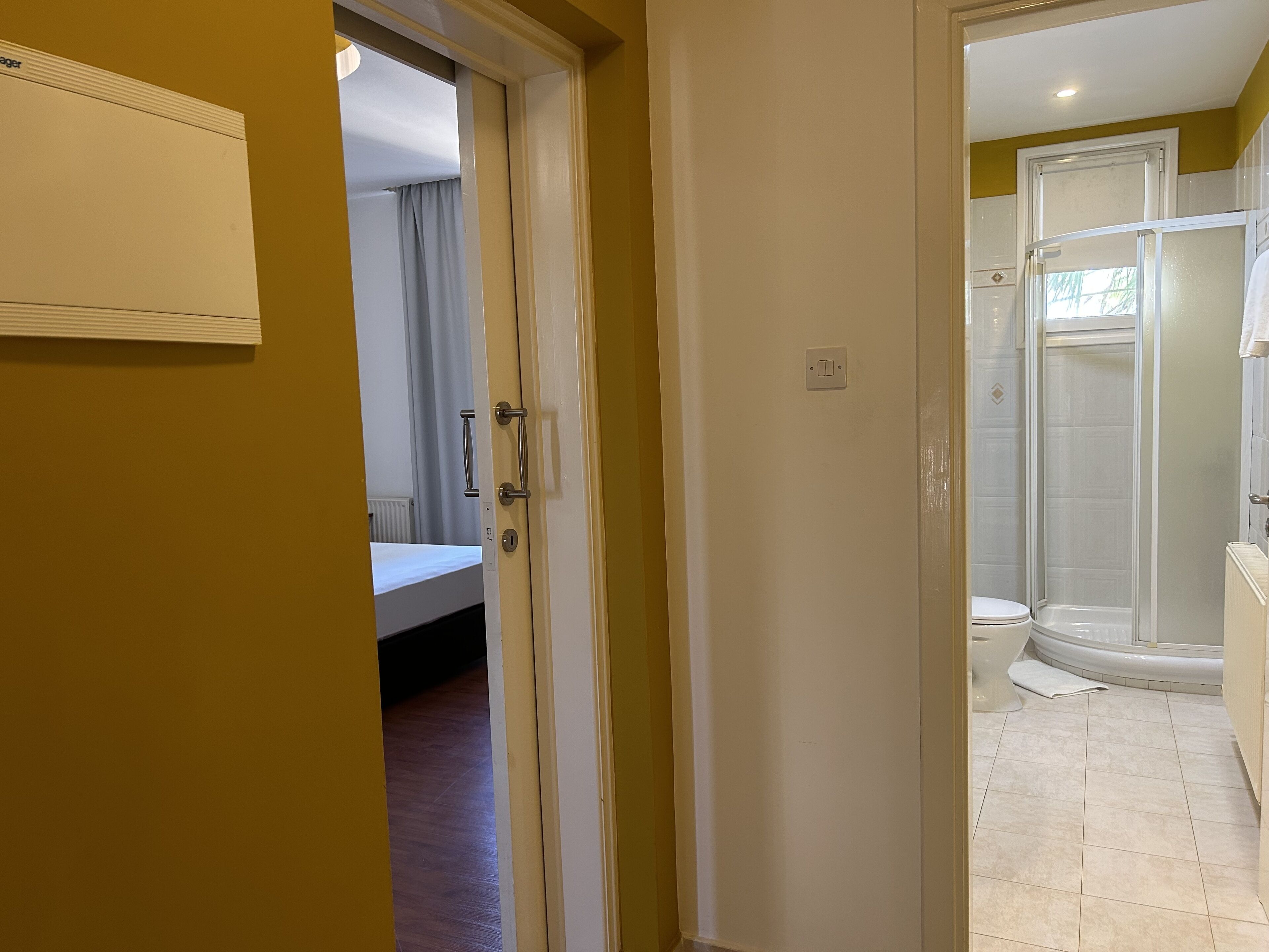 A hotel room with a bed, a bathroom with a shower, and a toilet.