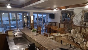A hotel lobby with a long reception counter, wooden chairs, and tables. There is a large window with a view of the outside. - Elena Boutique Residence (Larnaca)