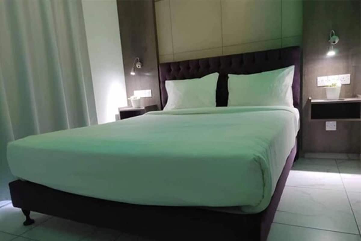 Una cama bien hecha con cabecera oscura y ropa de cama blanca en una habitación de hotel.