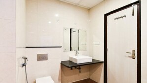 Un baño pequeño y moderno con un inodoro blanco, un lavabo con encimera negra y un espejo sobre el lavabo.
