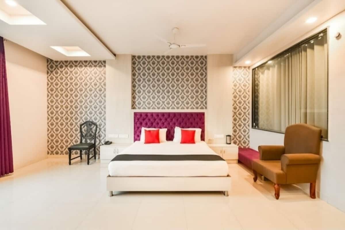 Une chambre à coucher avec un lit, une chaise, une table de chevet et un papier peint à motifs.