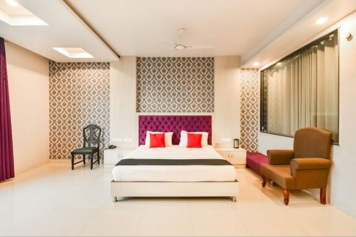 Une chambre moderne avec un grand lit, une tête de lit violette et une fenêtre avec des rideaux.