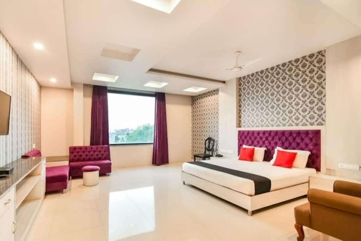 Une chambre d’hôtel moderne avec un grand lit, un canapé, une télévision et une fenêtre avec des rideaux.
