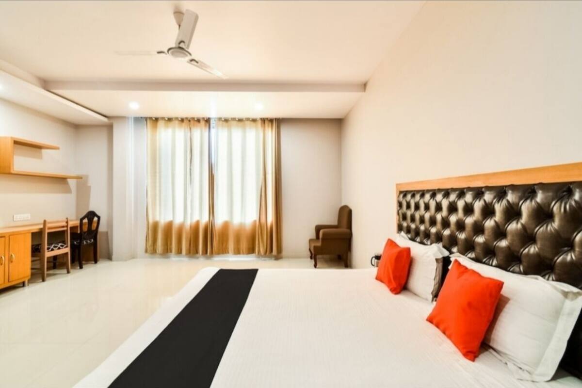 Une chambre d’hôtel avec un lit, un bureau, une chaise et un ventilateur de plafond.