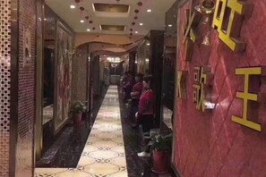 A hallway with a tiled floor, potted plants, and a red wall with yellow text. - Kaisheng Hotel (Xiangtan)