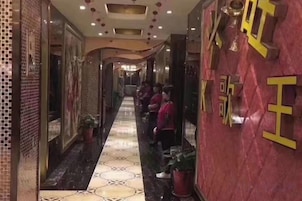 A hallway with a tiled floor, potted plants, and a red wall with yellow text.