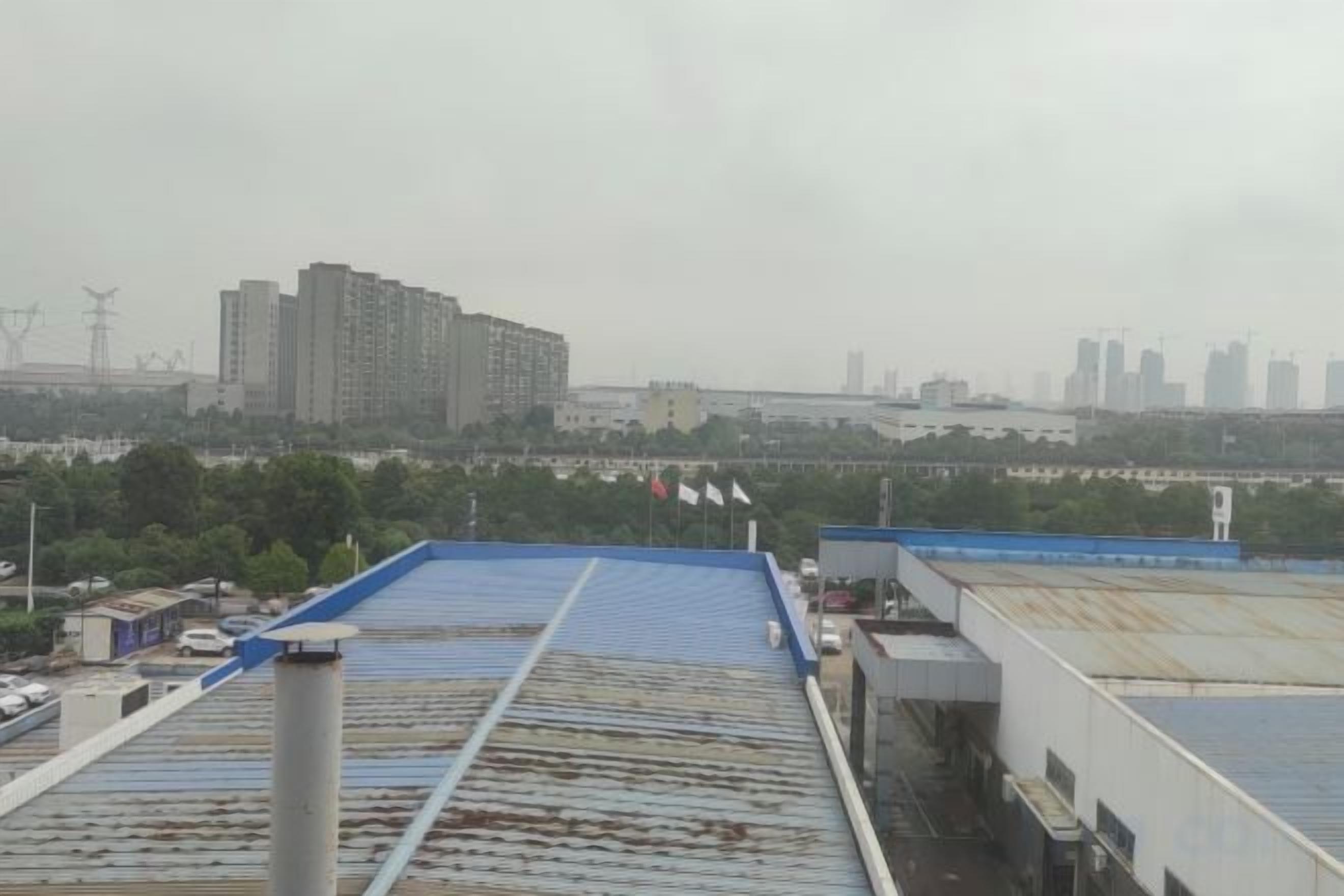 Una azotea con techo azul, estructura metálica y vistas a edificios lejanos.