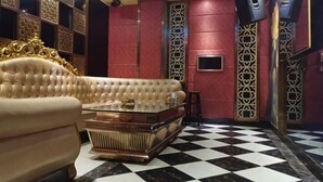 Une chambre luxueuse avec un canapé capitonné, une table basse en verre, un sol à carreaux et des panneaux décoratifs sur les murs.