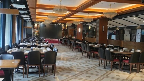 Un restaurant doté de nombreuses tables et chaises, d’un sol à motifs et de lustres suspendus.