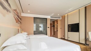 Une chambre d’hôtel moderne équipée d’un grand lit, d’une télévision et d’une armoire.