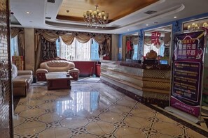 Um hall de hotel com balcão de recepção, área de estar e um candelabro.
