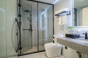 Un baño moderno con ducha de vidrio, inodoro blanco y tocador con espejo.